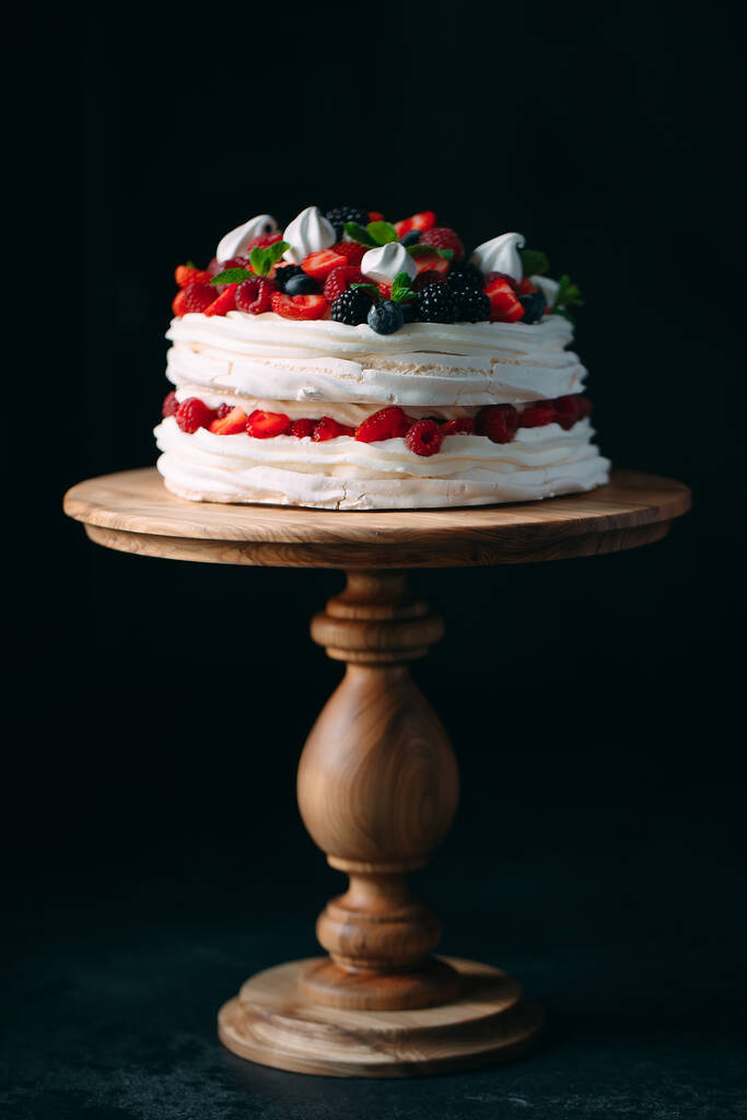 Фруктовый пирог. Торт украшен ягодами на деревянном стенде на черном фоне. - Фото, изображение