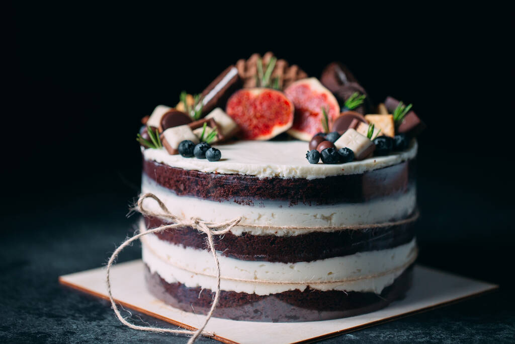 Фруктовый торт украшен инжиром, печеньем и черникой. - Фото, изображение