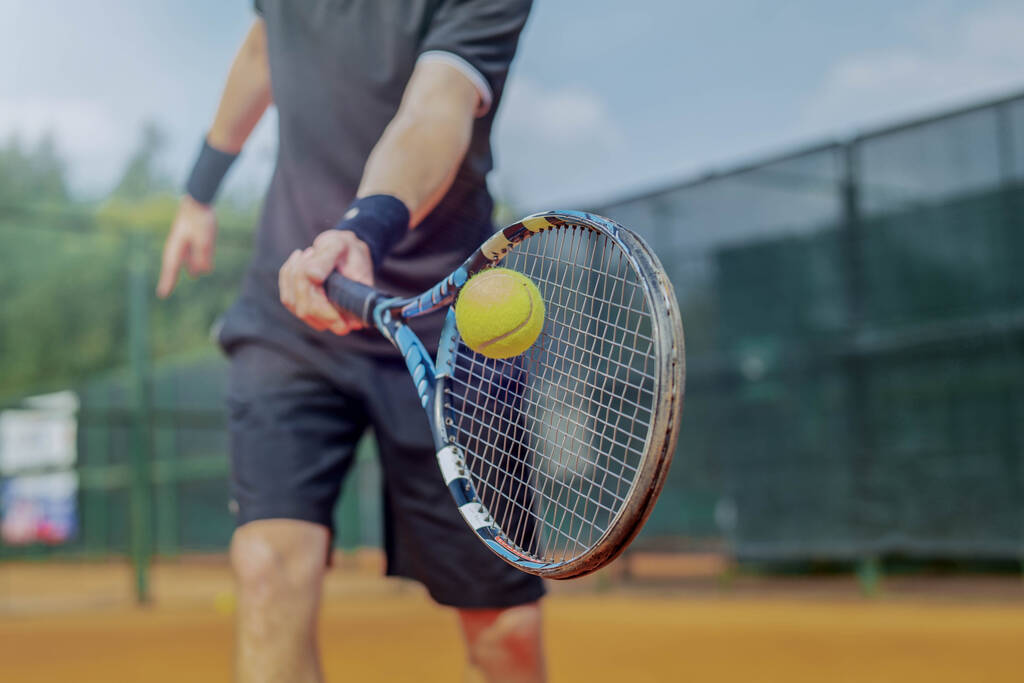 Zbliżenie człowieka grającego w tenisa i bijącego piłkę rakietą. - Zdjęcie, obraz