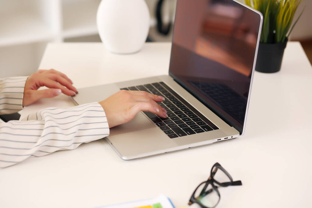 Mujer sentada en el escritorio y trabajando en las manos del ordenador de cerca - Foto, imagen