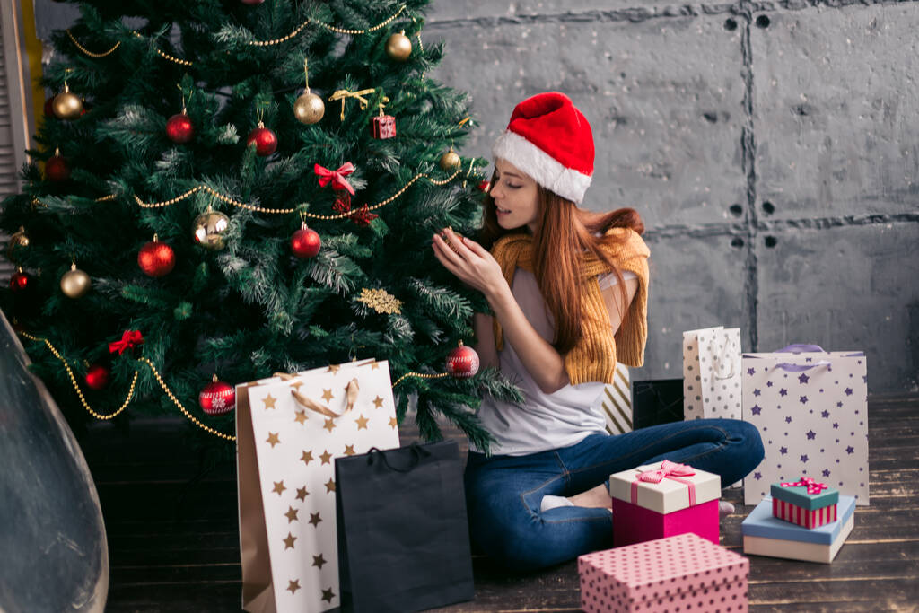 приваблива руда дівчина прикрашає новорічну ялинку
 - Фото, зображення