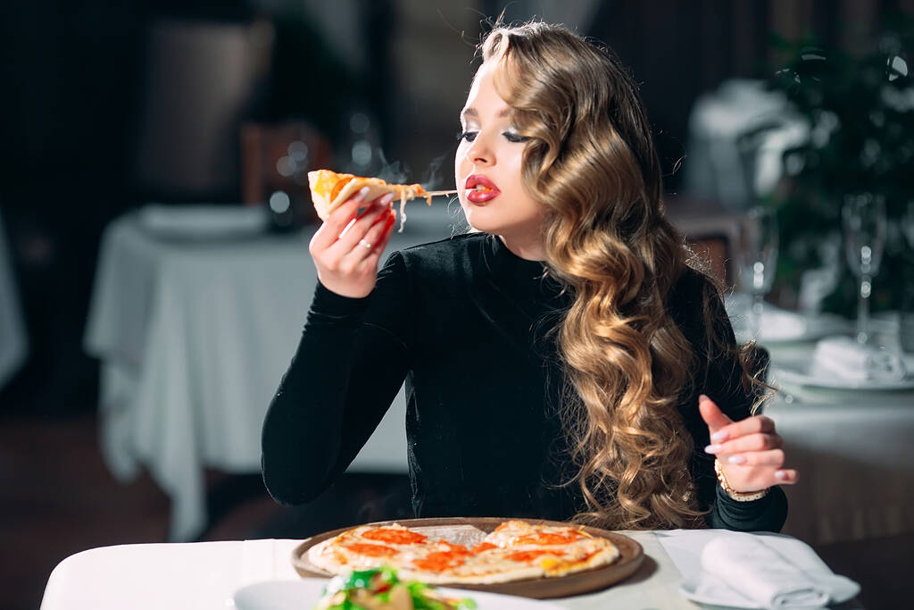 Junge schöne Mädchen allein Pizza essen in einem Restaurant. - Foto, Bild