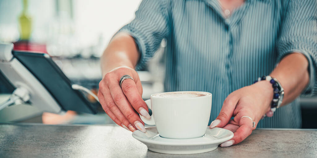 Detailní ženské barista ruce drží šálek aromatické latte nebo cappuccino kávy v baru nebo kavárně - Fotografie, Obrázek