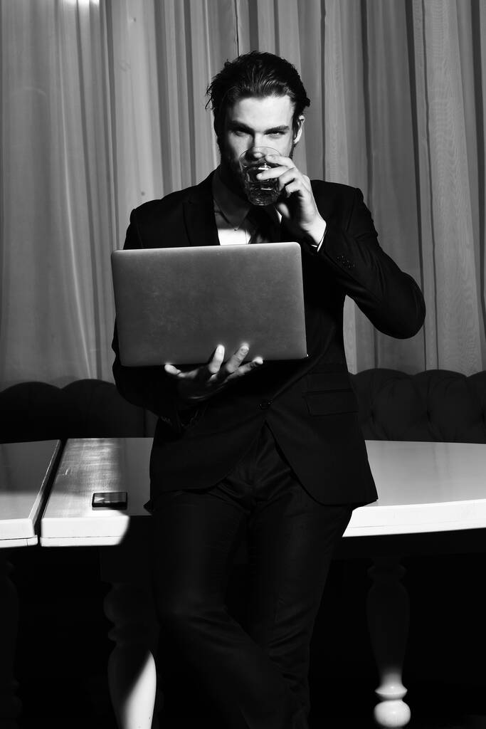 szakállas férfi, üzletember egy pohár whiskey-vel, mobil, laptop - Fotó, kép