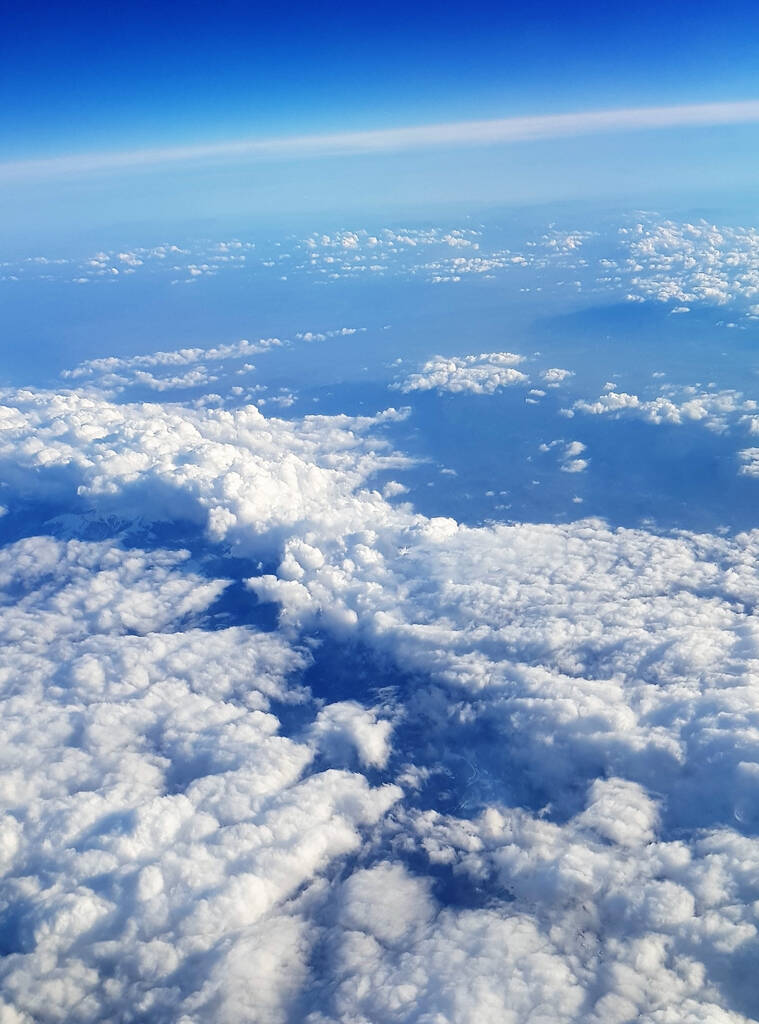 Un hermoso paisaje de la tierra y nubes blancas y esponjosas vistas desde un avión - Foto, Imagen