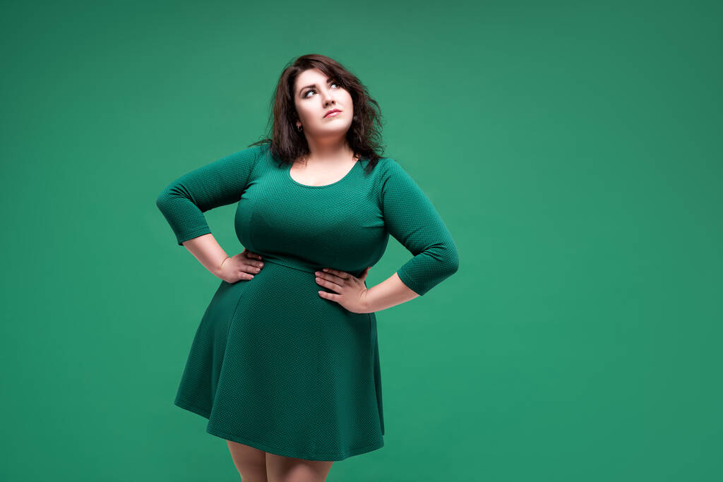 Plus rozmiar modelka w zielonej sukience, gruba kobieta na zielonym tle studio, ciało pozytywne pojęcie - Zdjęcie, obraz
