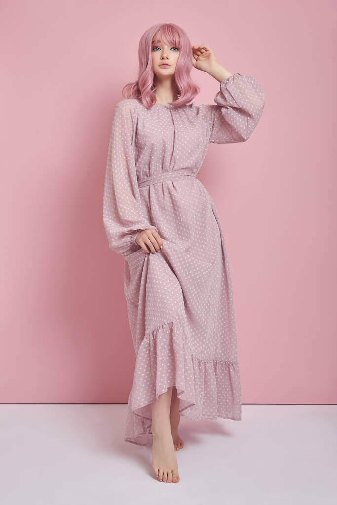 Mujer con el pelo teñido de rosa en un vestido largo. Retrato de una chica con coloración de cabello en la pared rosa. Peinado perfecto y peinado - Foto, Imagen