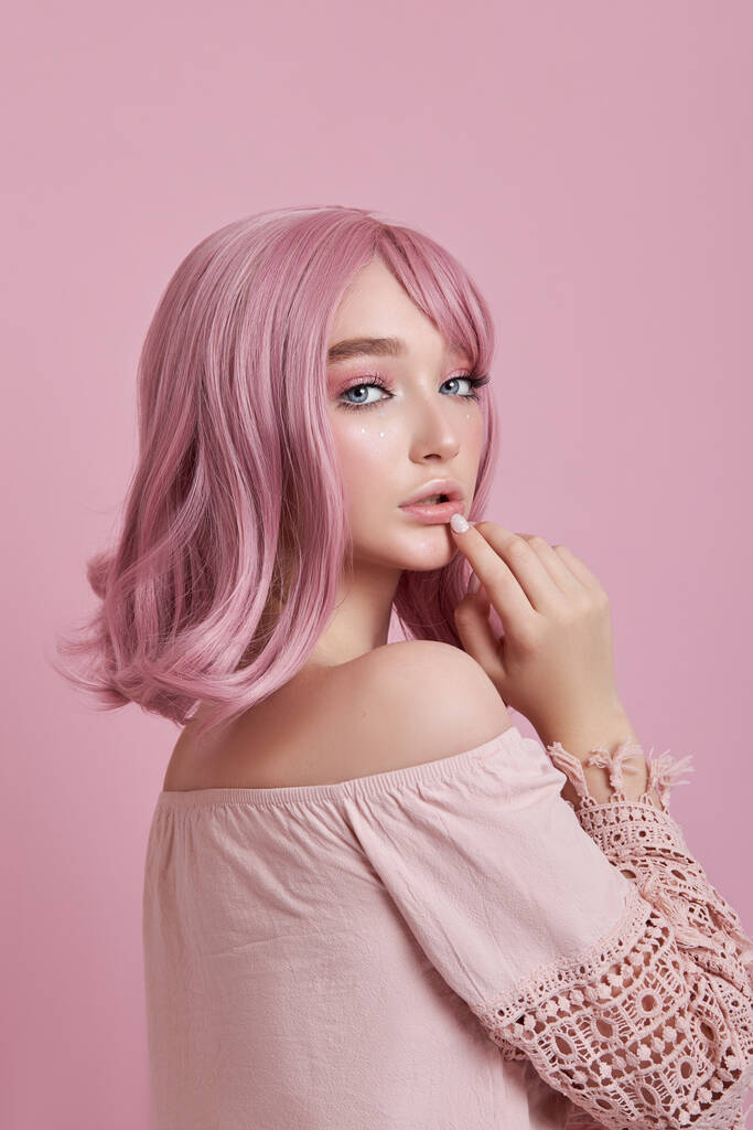 Portret van een sexy jonge vrouw met roze haar. Perfect kapsel en haarkleuring. Meisje met mooie blauwe ogen en lang roze haar - Foto, afbeelding