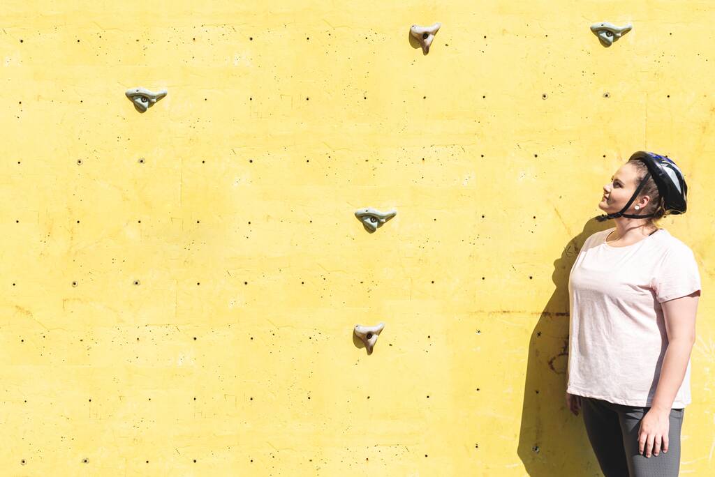 Избыточный вес женщины глядя вверх на искусственные стены восхождения - Фото, изображение