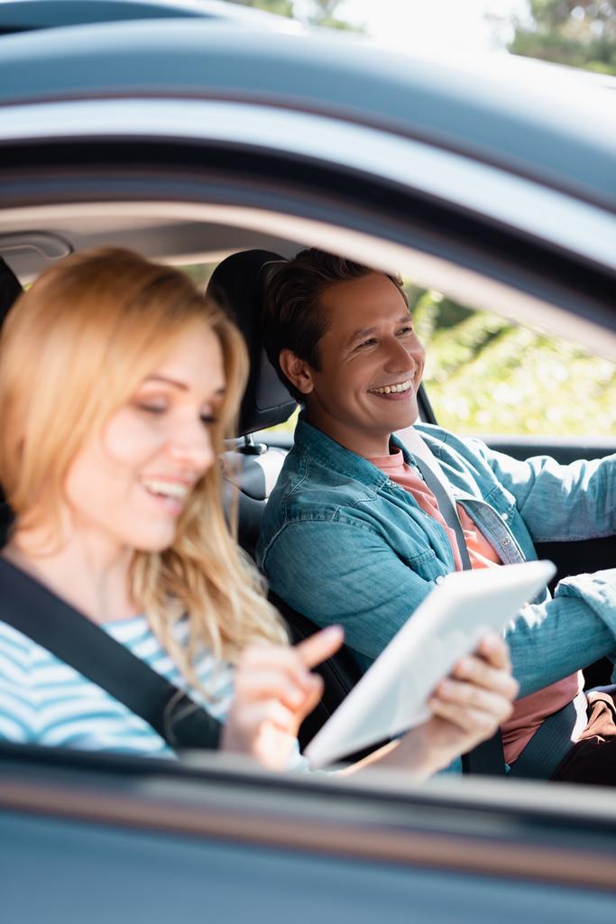 Szelektív fókusz férfi vezetés autó közelében feleség segítségével digitális tabletta  - Fotó, kép