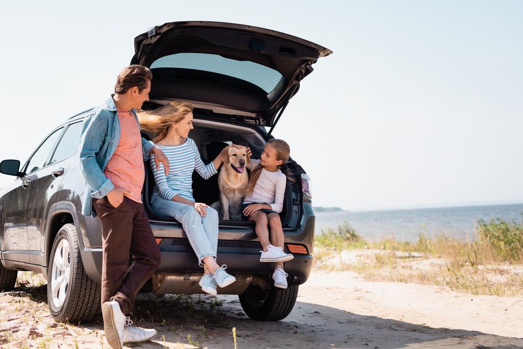Επιλεκτική εστίαση της οικογένειας με golden retriever που ταξιδεύουν σε αυτοκίνητο στην παραλία  - Φωτογραφία, εικόνα
