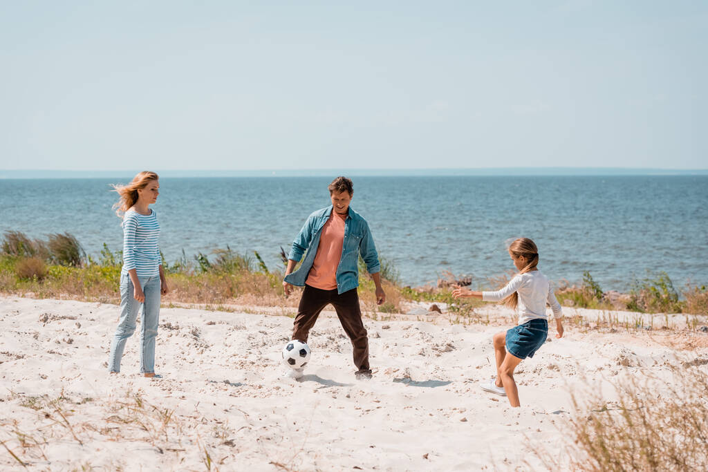 Focus selettivo della famiglia che gioca a calcio sulla spiaggia  - Foto, immagini