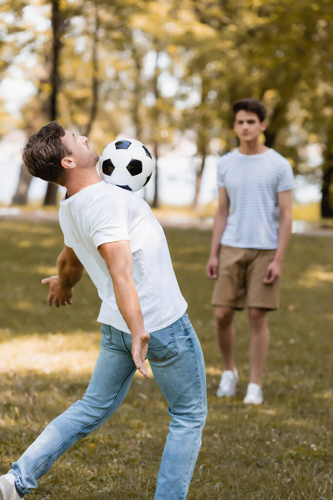επιλεκτική εστίαση του πατέρα παίζει ποδόσφαιρο με έφηβος γιος - Φωτογραφία, εικόνα