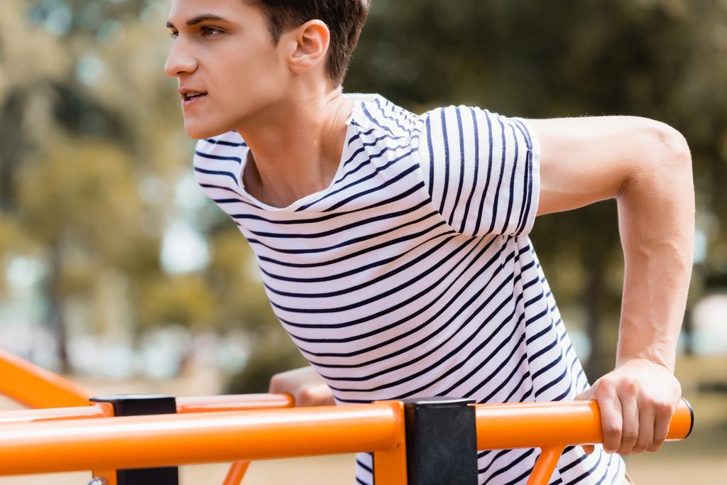 sterke tiener jongen oefenen op horizontale bars - Foto, afbeelding