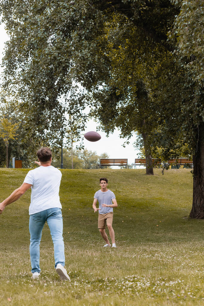 グリーンパークの10代の息子にラグビーボールを投げ込む父親の姿を  - 写真・画像