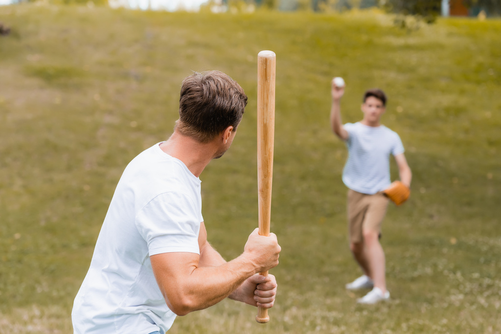 10代の息子と野球をしながらソフトボールのバットを持っている父親の  - 写真・画像