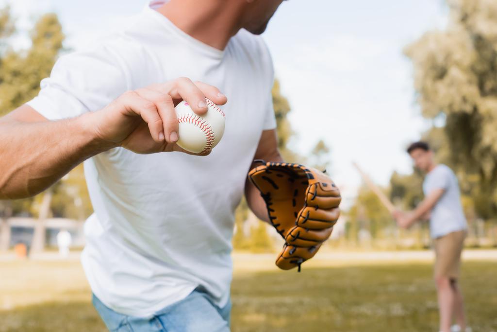 καλλιεργημένη άποψη του άνδρα με δερμάτινο γάντι παίζει μπέιζμπολ με έφηβος γιος στο πάρκο  - Φωτογραφία, εικόνα