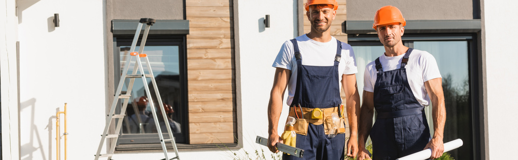 Horizontal crop of builders in uniform holding tools and blueprint near building  - Photo, Image
