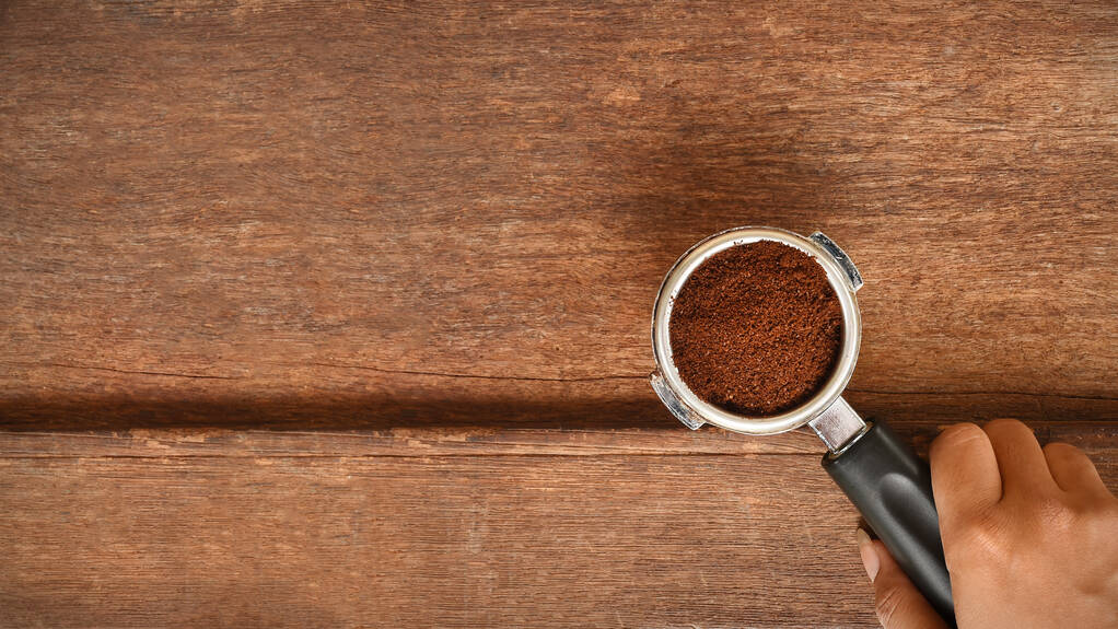 świeżo zmielona ziarno kawy w filtrze porta przez młynek do kawy palonej zrobić fasolę w proszku. - Zdjęcie, obraz