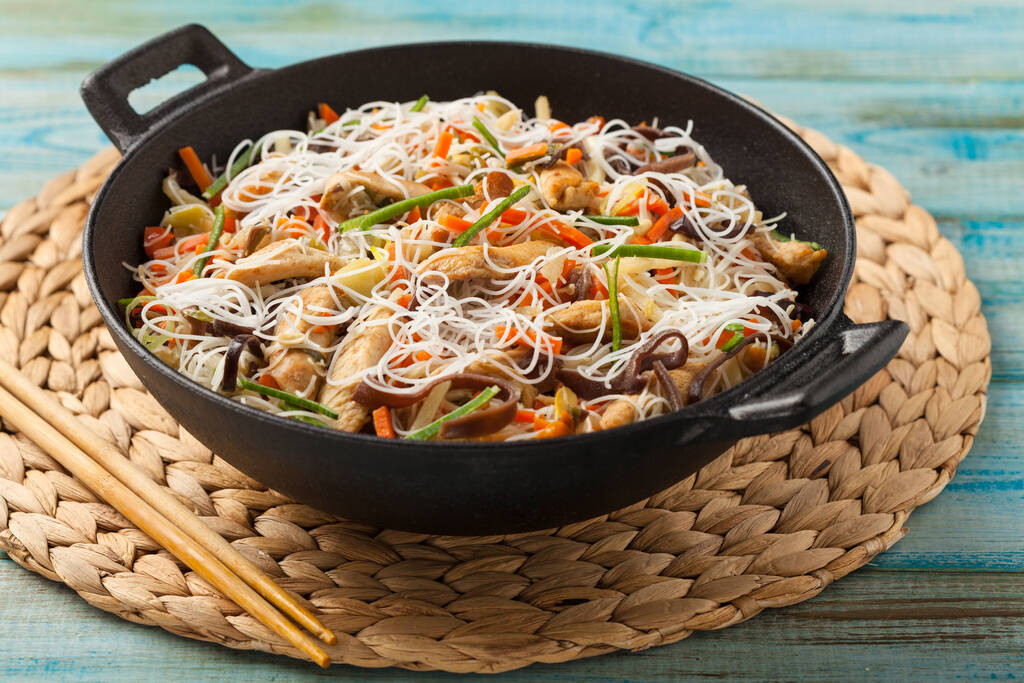 Nouilles de riz au poulet, champignons et légumes, préparées au wook.  - Photo, image