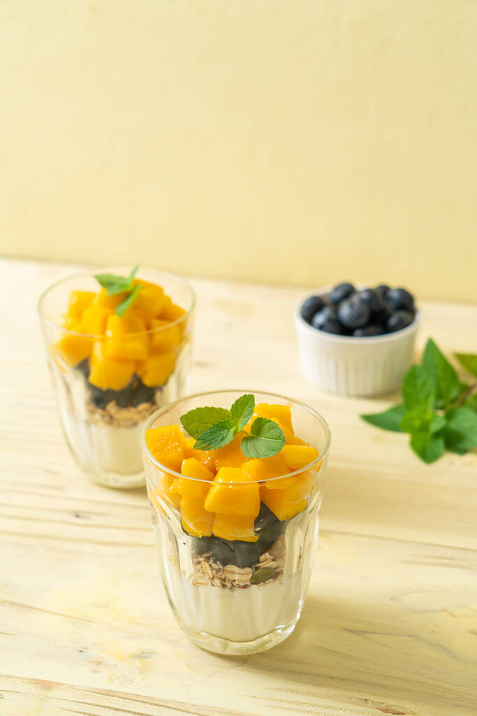 kotitekoista tuoretta mangoa ja tuoretta mustikkaa jogurtilla ja myslillä - terveellinen ruokatyyli - Valokuva, kuva