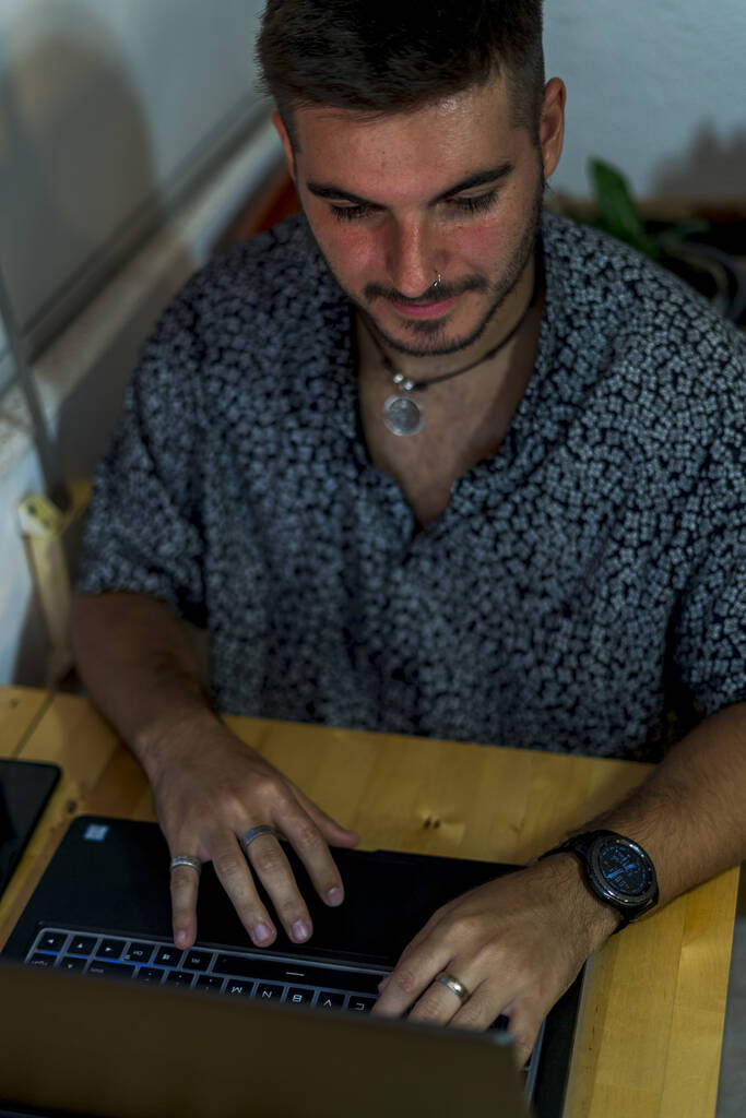 Вертикальный снимок европейского мужчины, работающего с ноутбуком дома - Фото, изображение