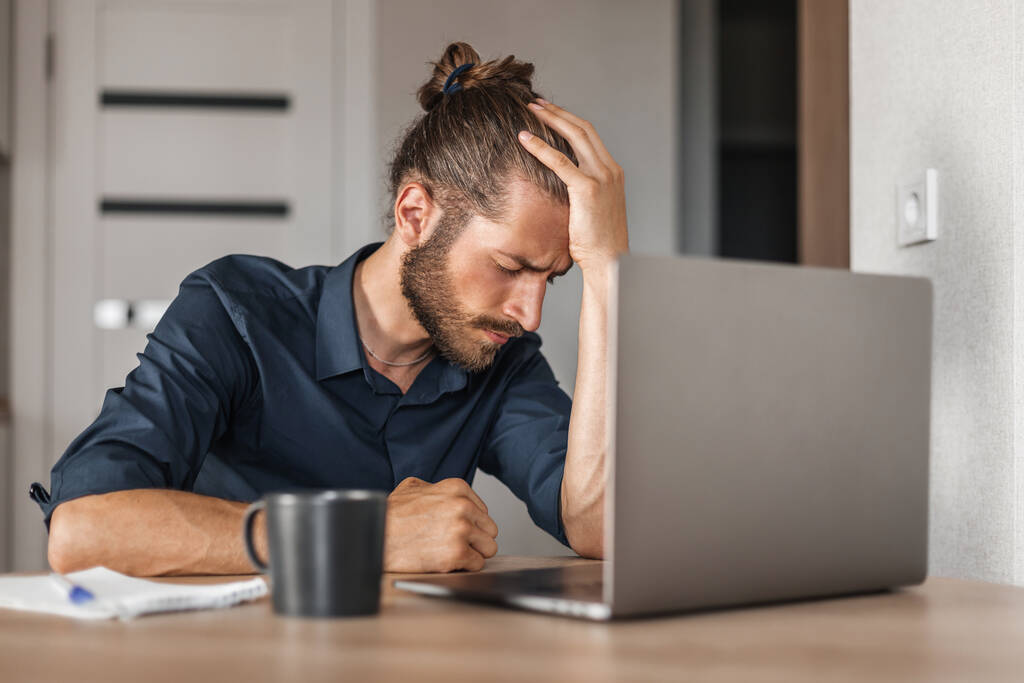 Hombre cansado con dolor de cabeza trabajando en casa usando portátil - Foto, Imagen