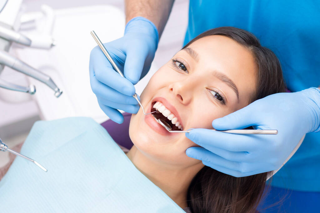 Atraktivní mladá žena na zubní klinice s mužským zubařem. Zdravé zuby koncept. - Fotografie, Obrázek