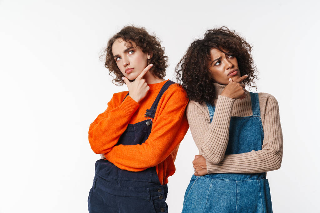 Portrait of displeased multinational women in overalls thinking and looking upward isolated over white background - Photo, Image