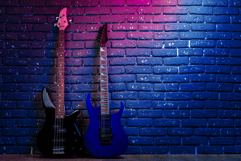 Ηλεκτρική κιθάρα σε νέον φως κατά σκοτεινό τοίχο - Φωτογραφία, εικόνα