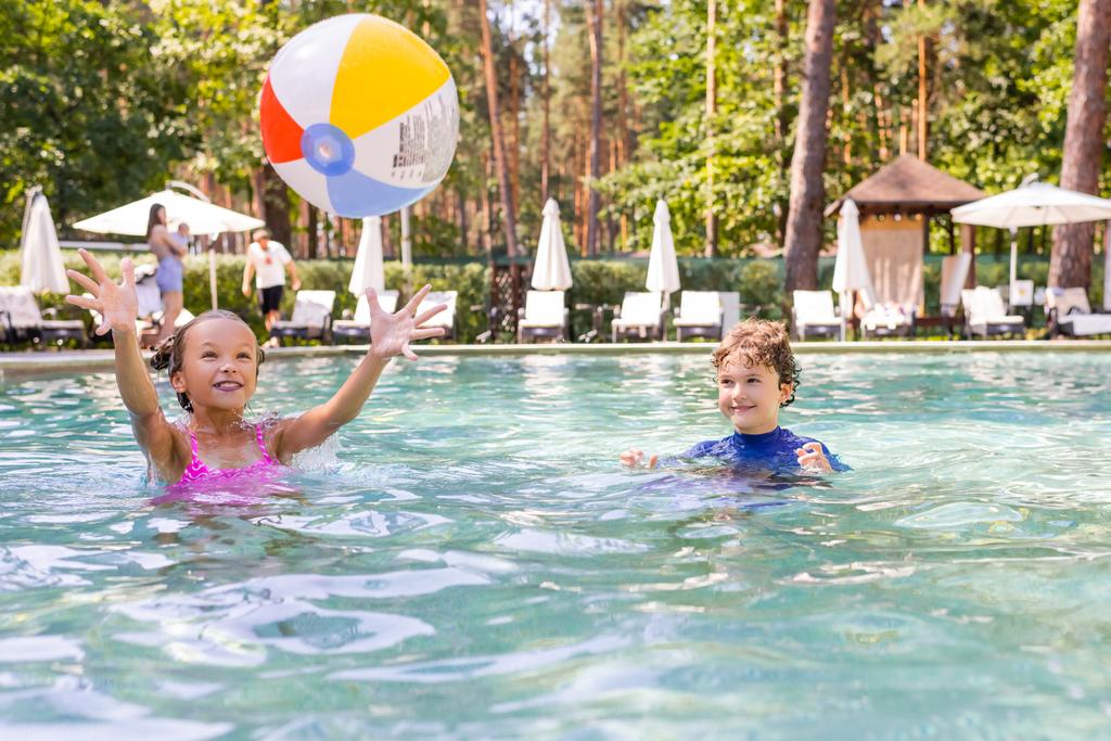 enfoque selectivo de amigos emocionados jugando con la bola inflable en la piscina - Foto, Imagen