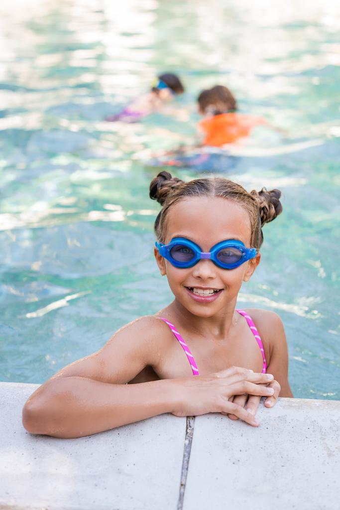 Yüzme gözlüklü çocuk havuz başında kameraya bakıyor. - Fotoğraf, Görsel