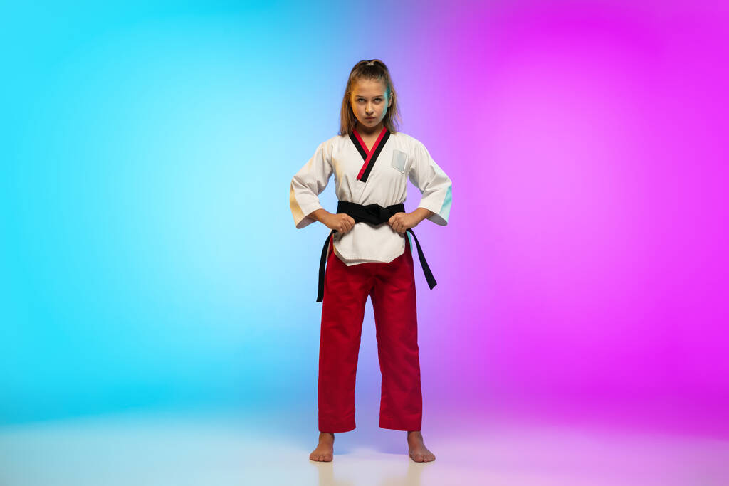 Karate, chica taekwondo con cinturón negro aislado sobre fondo degradado en luz de neón - Foto, Imagen