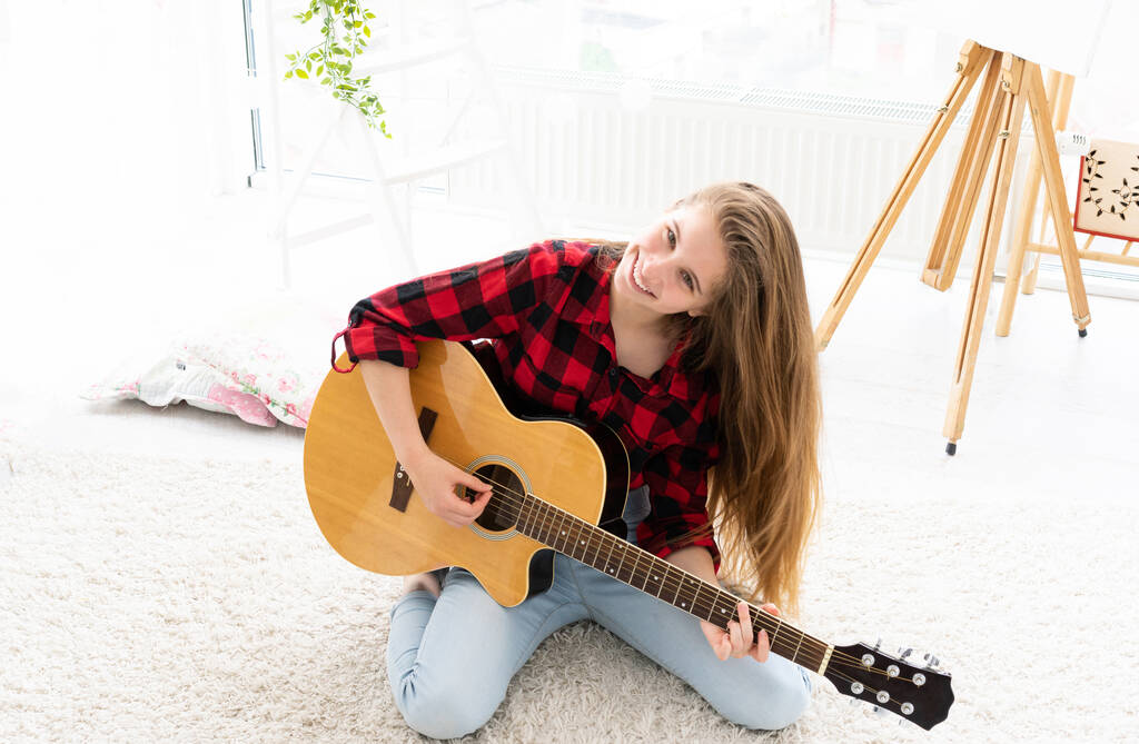 Nettes Mädchen spielt Gitarre im hellen Raum - Foto, Bild