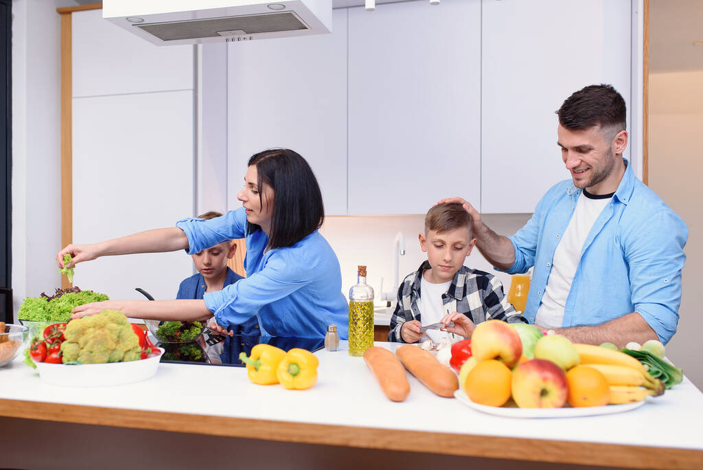 Feliz familia elegante preparando una cena saludable en la cocina moderna y luminosa juntos. Precioso concepto familiar. - Foto, Imagen
