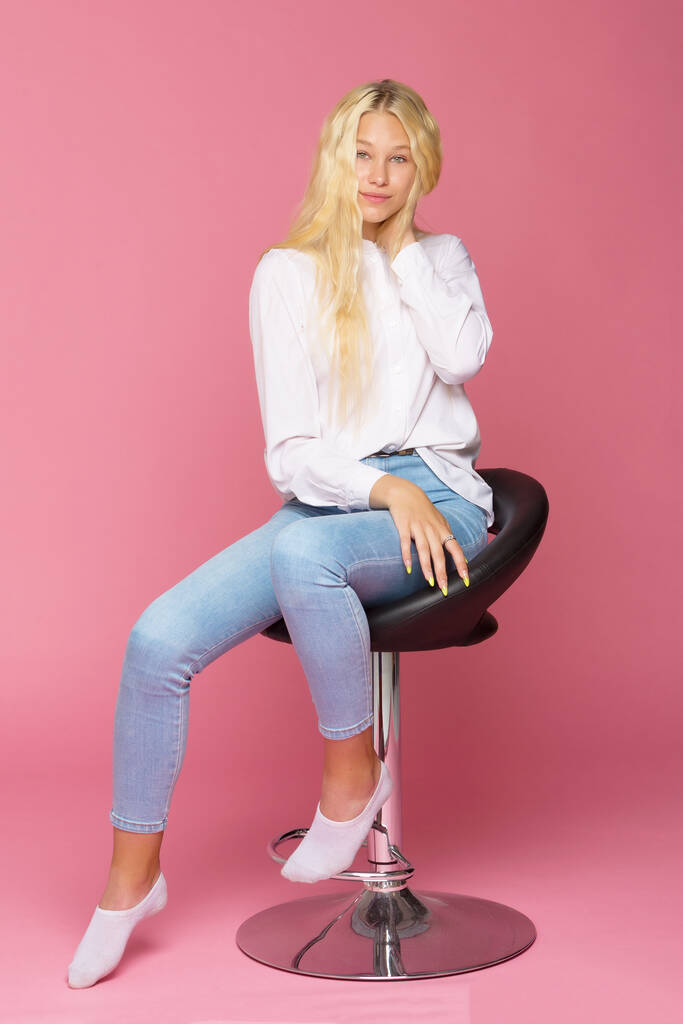Niedliches Lächeln Blondes Mädchen sitzt auf Hochstuhl im Studio - Foto, Bild