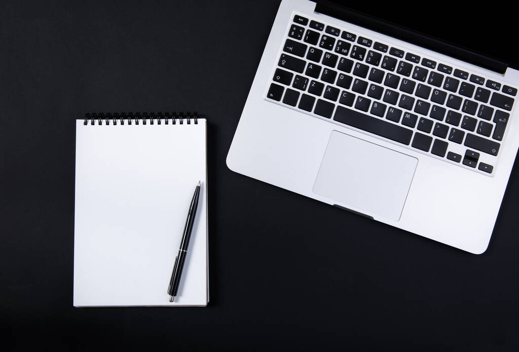 Scrivania da ufficio nera con laptop, taccuino e penna mockup bianchi. Vista dall'alto  - Foto, immagini
