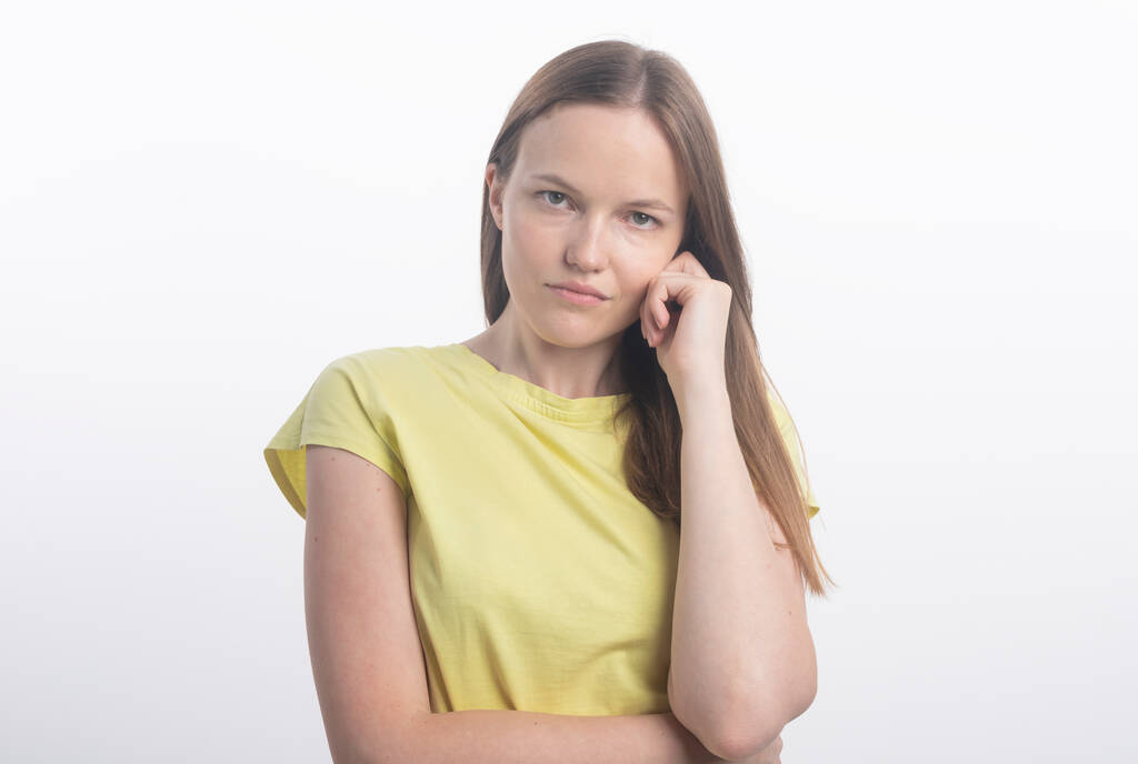 Portret van een jonge vrouw op een witte achtergrond. serieuze vrouw kijken naar camera aandachtig met de hand in de buurt van oor, studio - Foto, afbeelding