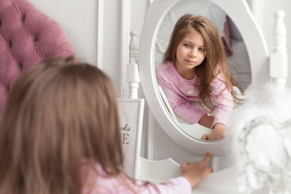 Красивая девочка-подросток у зеркала у кровати. - Фото, изображение