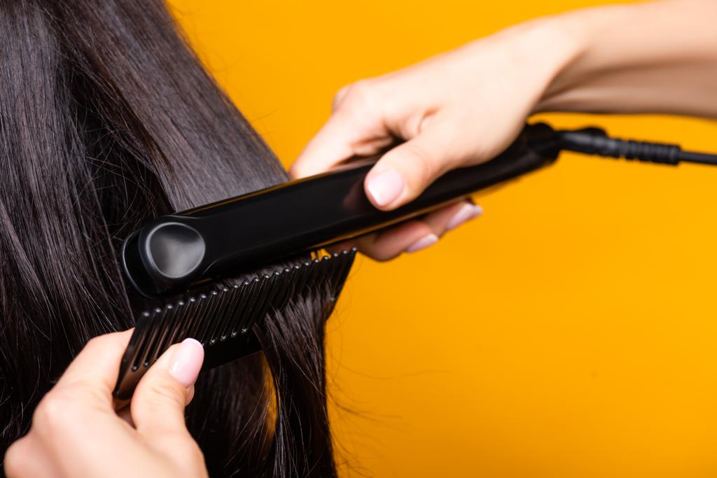 обрізаний вид перукаря з використанням випрямлення волосся і гребінця ізольований на жовтому
 - Фото, зображення