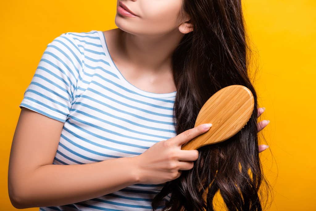 vue recadrée de la femme brune brossant les cheveux isolés sur jaune - Photo, image