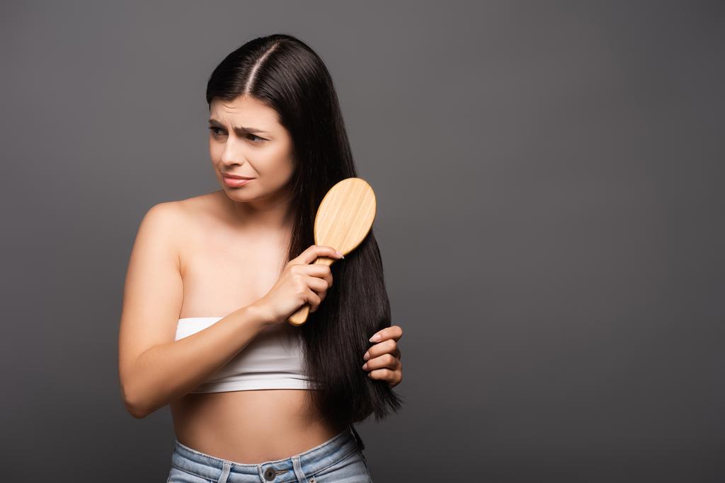 triste bruna donna spazzolatura capelli isolati su nero - Foto, immagini