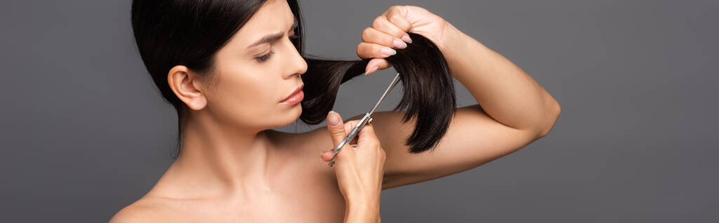 nahá bruneta žena stříhání vlasy izolované na černé, panoramatický výstřel - Fotografie, Obrázek