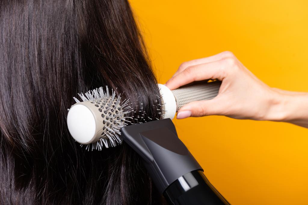 обрізаний вид перукаря з використанням фену та пензля ізольовані на жовтому
 - Фото, зображення