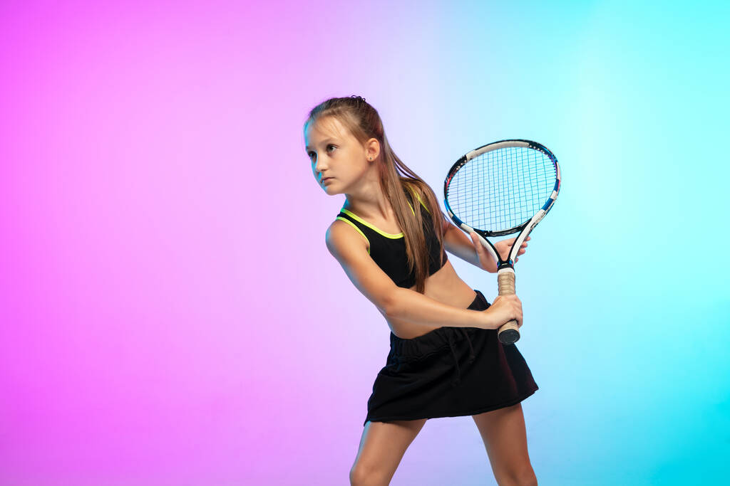 Siyah spor giyimli küçük tenisçi kız neon ışıklı arka planda izole edilmiş. - Fotoğraf, Görsel