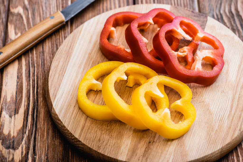 colorful sliced bell peppers on wooden cutting board near knife - Photo, Image