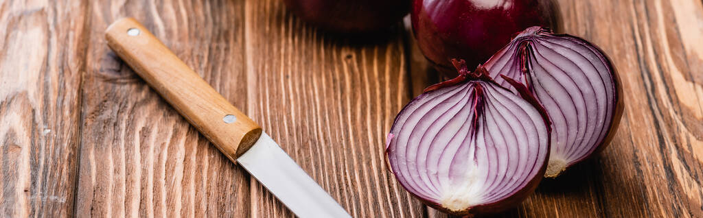 cortar cebolla roja cerca de cuchillo en mesa de madera, tiro panorámico - Foto, Imagen