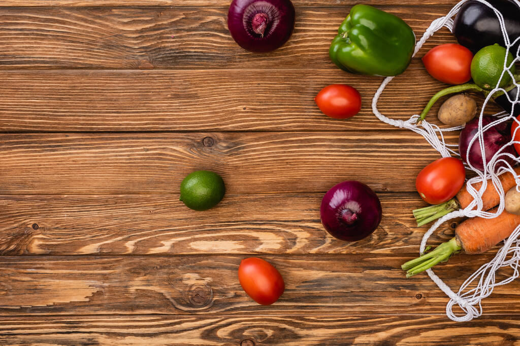 vue du dessus des légumes frais mûrs éparpillés du sac à ficelle sur la table en bois - Photo, image
