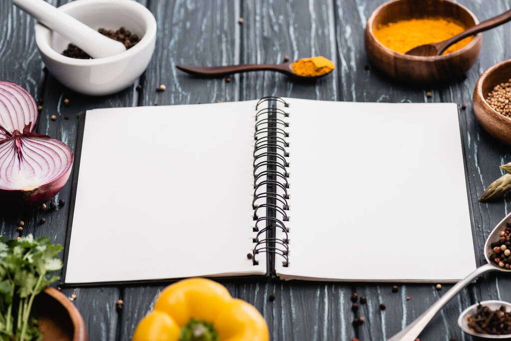 selectieve focus van verse kleurrijke groenten en specerijen in de buurt van blanco notebook op houten oppervlak - Foto, afbeelding