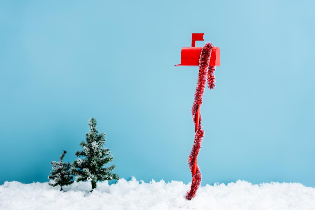 червона поштова скринька з прикрасою біля сосен на білому снігу на синьому
 - Фото, зображення
